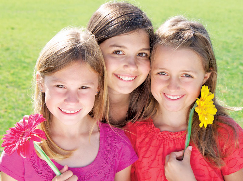 three smiling girls with flowers